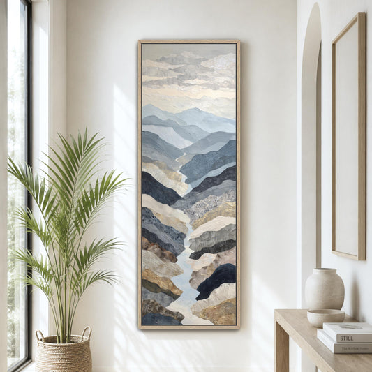 a large painting of mountains hanging on a wall, with a potted plant to the left and a wooden table with a vase to the right.