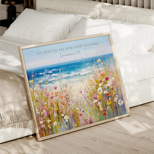 A framed painting depicting a serene landscape with a field of colorful flowers and a body of water, such as a lake or ocean, is displayed on a bed.