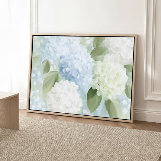 A large framed painting depicting a vibrant floral scene with white and blue hydrangeas and green leaves is displayed on a wooden floor against a white wall.