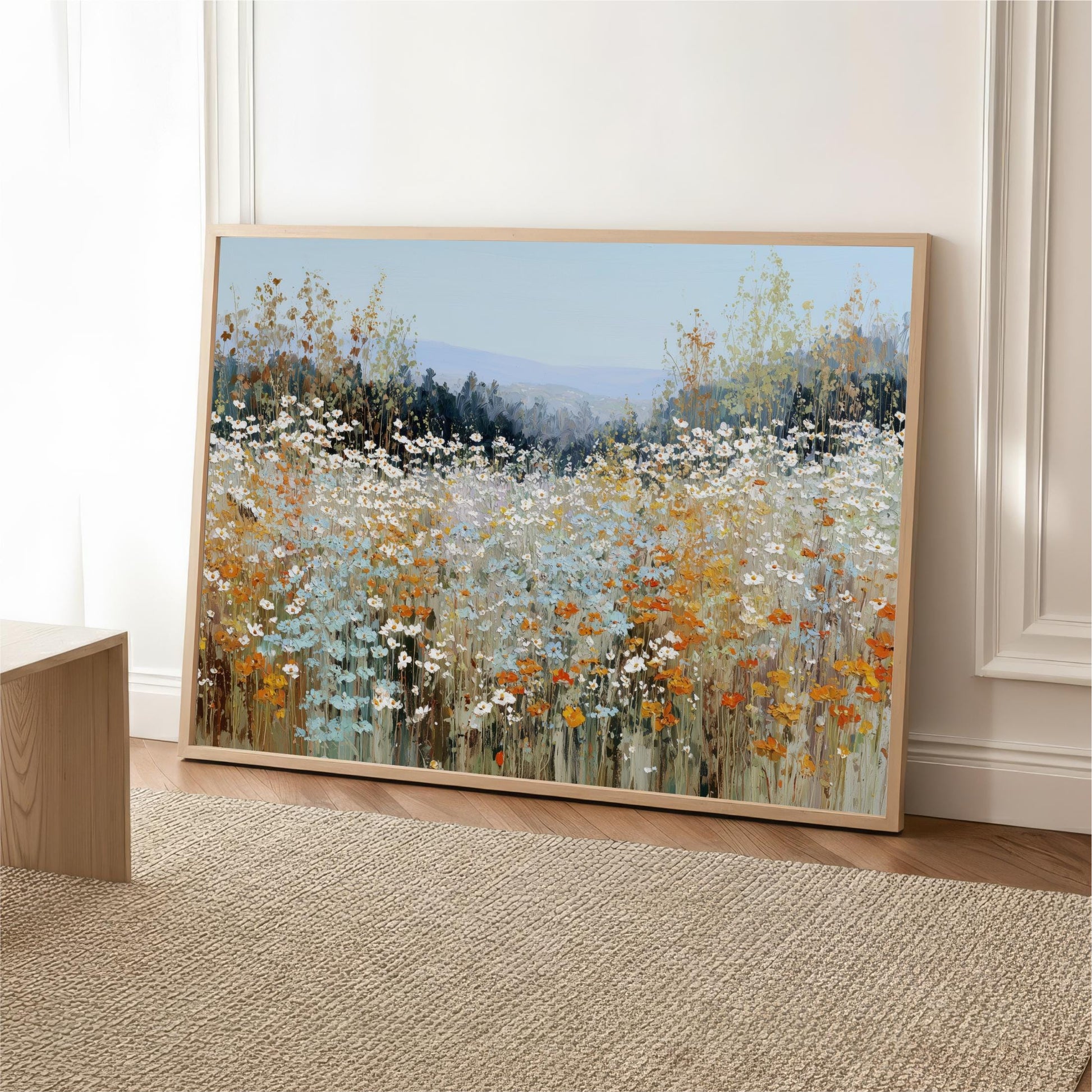 a large, framed painting of a field of flowers, with a variety of colors including white, orange, and green.
