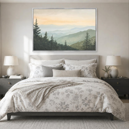 a serene bedroom scene with a large bed adorned with a floral comforter and pillows, flanked by two nightstands with lamps. Above the bed, a large framed landscape painting of a mountainous, forested area is displayed on the wall, creating a peaceful and tranquil atmosphere.