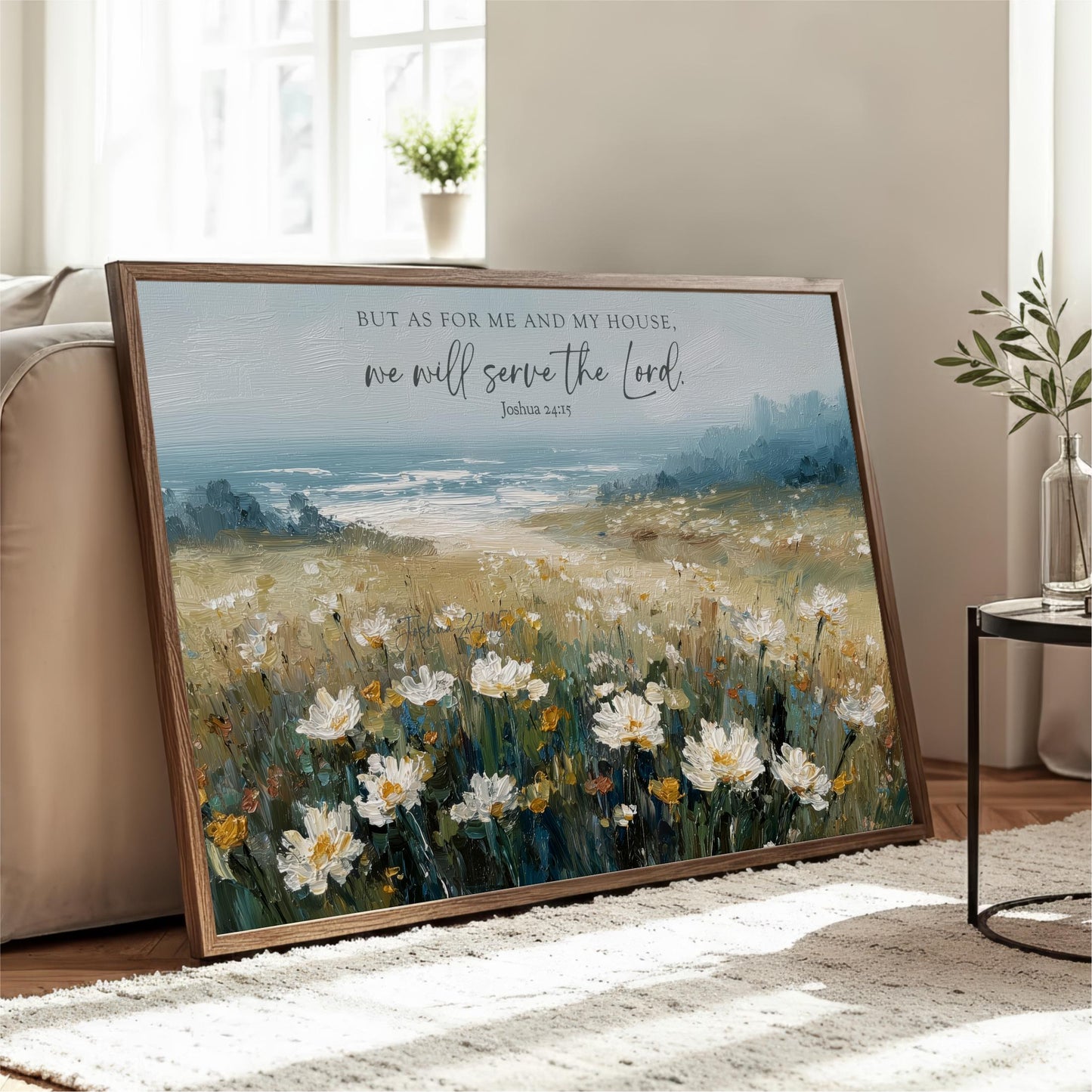 A framed painting depicting a field of white flowers with a blue sky and ocean in the background, accompanied by a Bible verse.