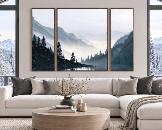 a large, three-panel landscape painting hanging on a wall above a white sectional sofa in a living room. The painting depicts a serene mountain scene with a lake and pine trees.