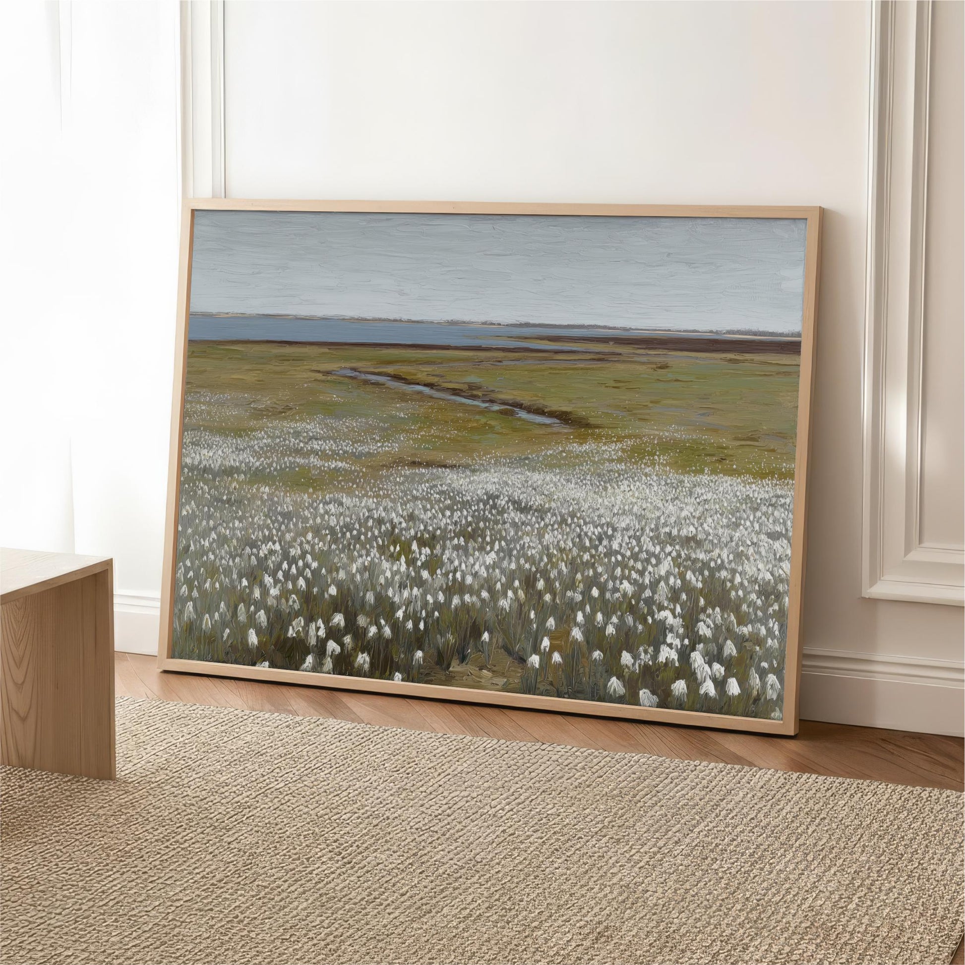 a large painting of a field with white flowers, displayed on a wall in a room.