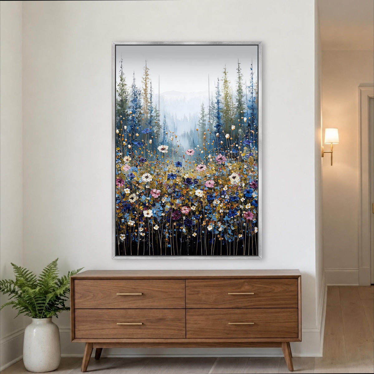 a large framed painting of a field of flowers hanging on a wall above a wooden dresser.
