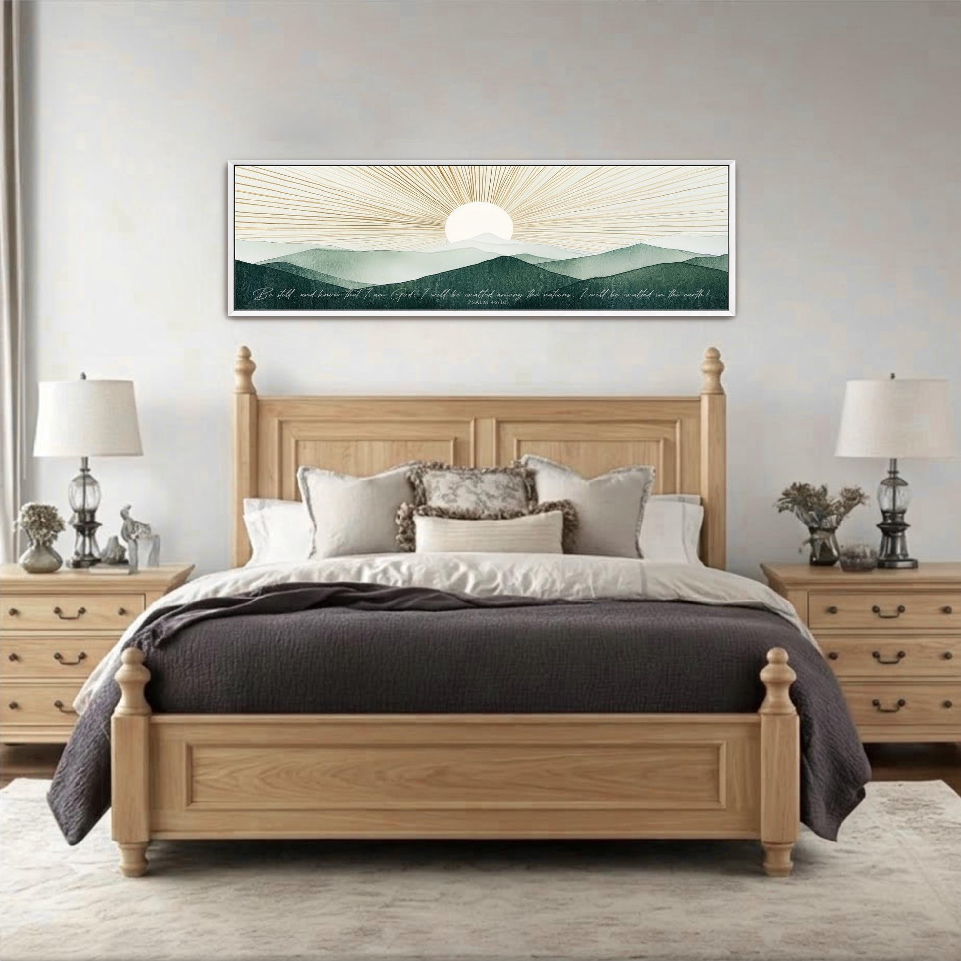a large wooden bed with a gray comforter and pillows, flanked by two nightstands with lamps. Above the bed is a framed artwork depicting a sunrise over mountains.