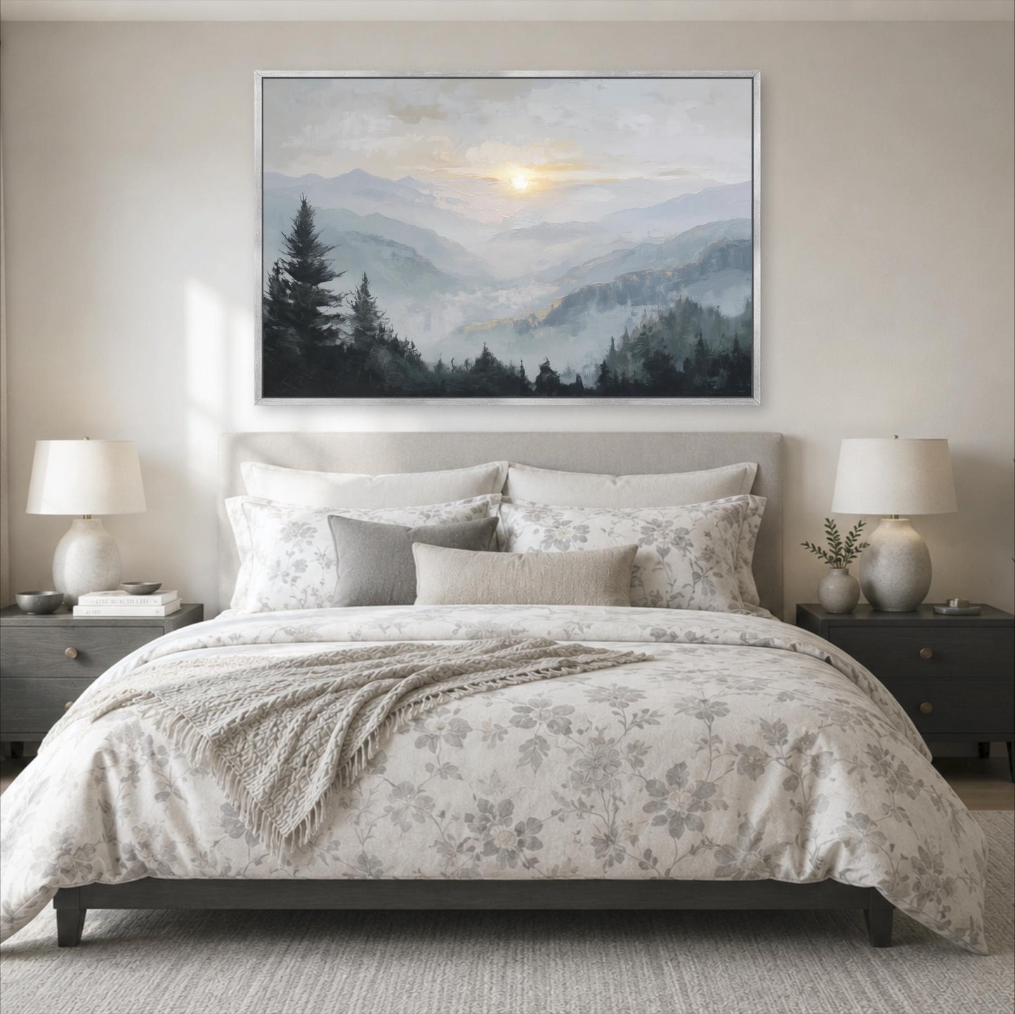 a serene bedroom scene with a large bed adorned with a floral comforter and pillows, flanked by two nightstands with lamps. Above the bed, a large painting of a mountain landscape with a sunset is displayed on the wall.