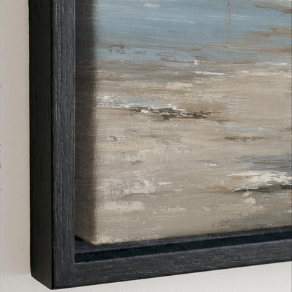 The image is a close-up of a framed painting depicting a landscape scene with a blue sky and a sandy beach.