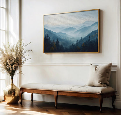 a serene indoor setting with a large framed landscape painting hanging on the wall above a wooden bench with a white cushion. The painting depicts a tranquil mountain scene with lush greenery and a misty atmosphere. A vase filled with white flowers is placed on the floor next to the bench, adding a touch of natural beauty to the space.