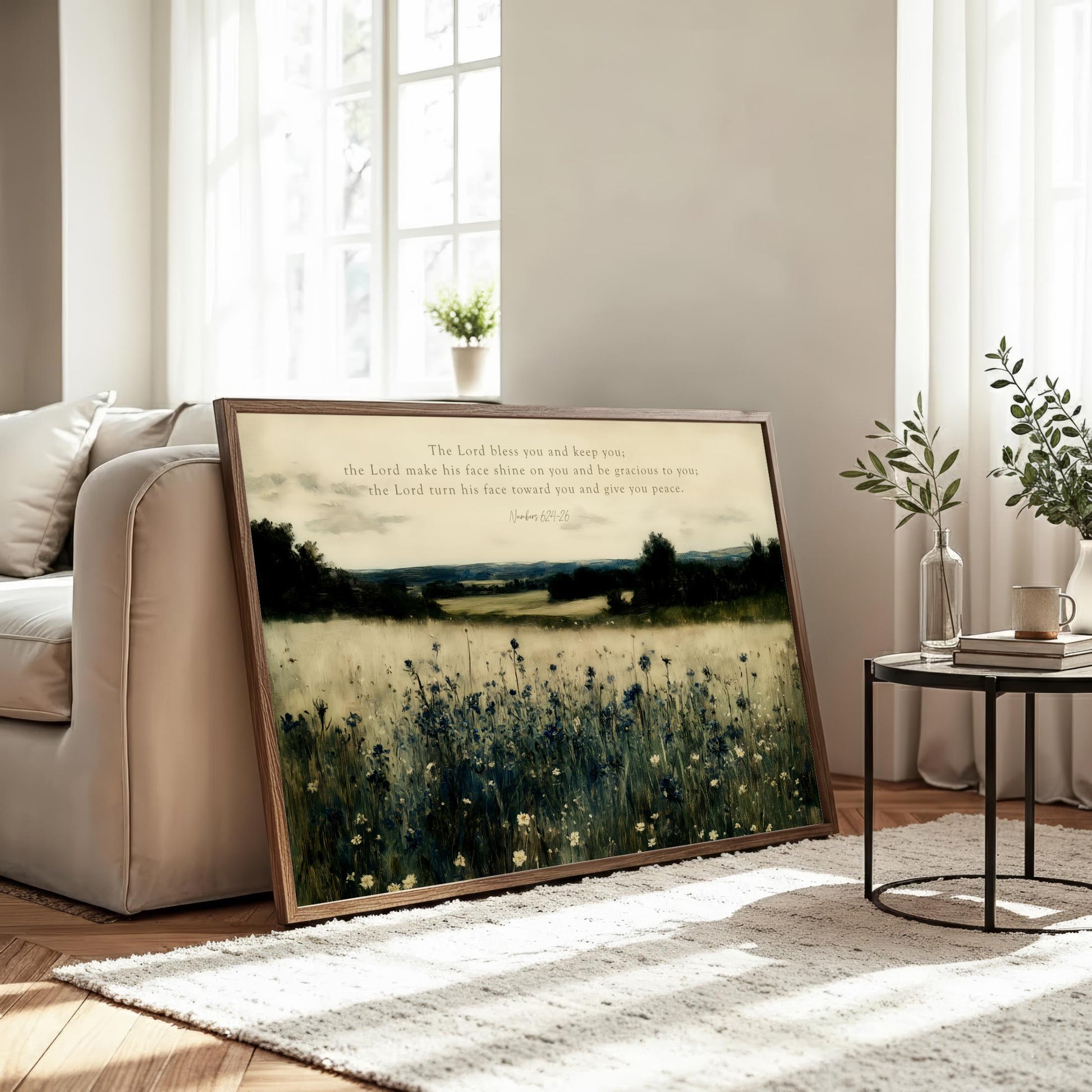 a large framed painting of a field with flowers, placed on a rug in a living room setting.