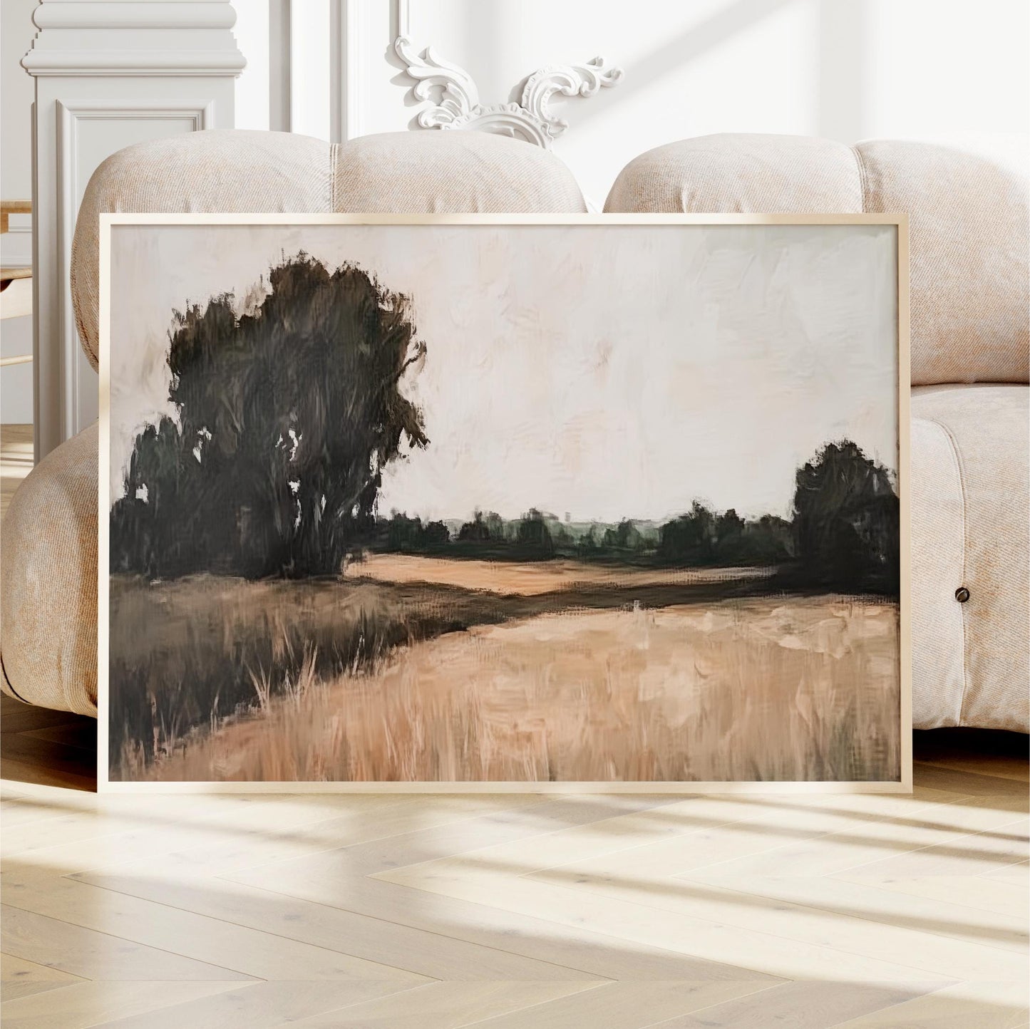 a large, framed painting depicting a serene landscape with a field and trees in the background.