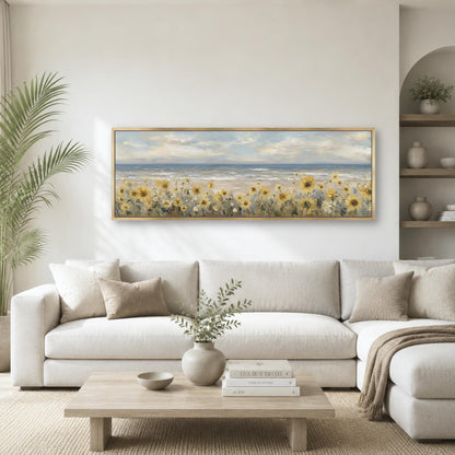a serene living room with a large painting of a field of yellow flowers hanging on the wall above a white sofa. The sofa is positioned in front of a wooden coffee table, which has a vase of greenery and a stack of books on it. The room also features a potted plant and a bookshelf, creating a cozy and inviting atmosphere.