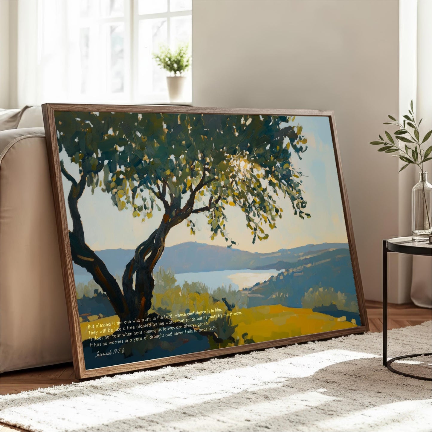 A large framed painting depicting a serene landscape with a tree and a body of water, placed on a white rug in a living room.