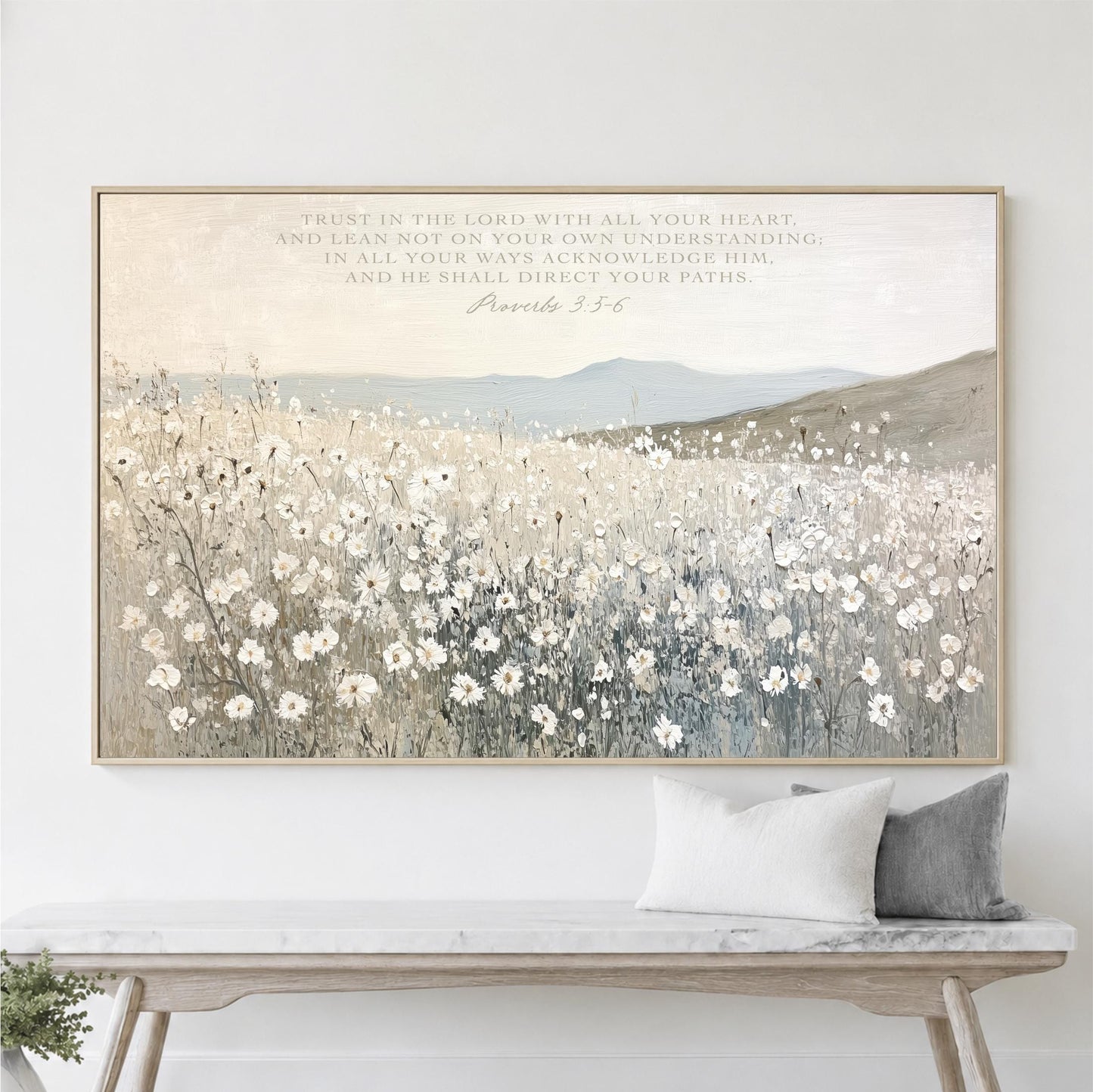 a large framed painting of a field of white flowers hanging on a wall above a wooden bench.