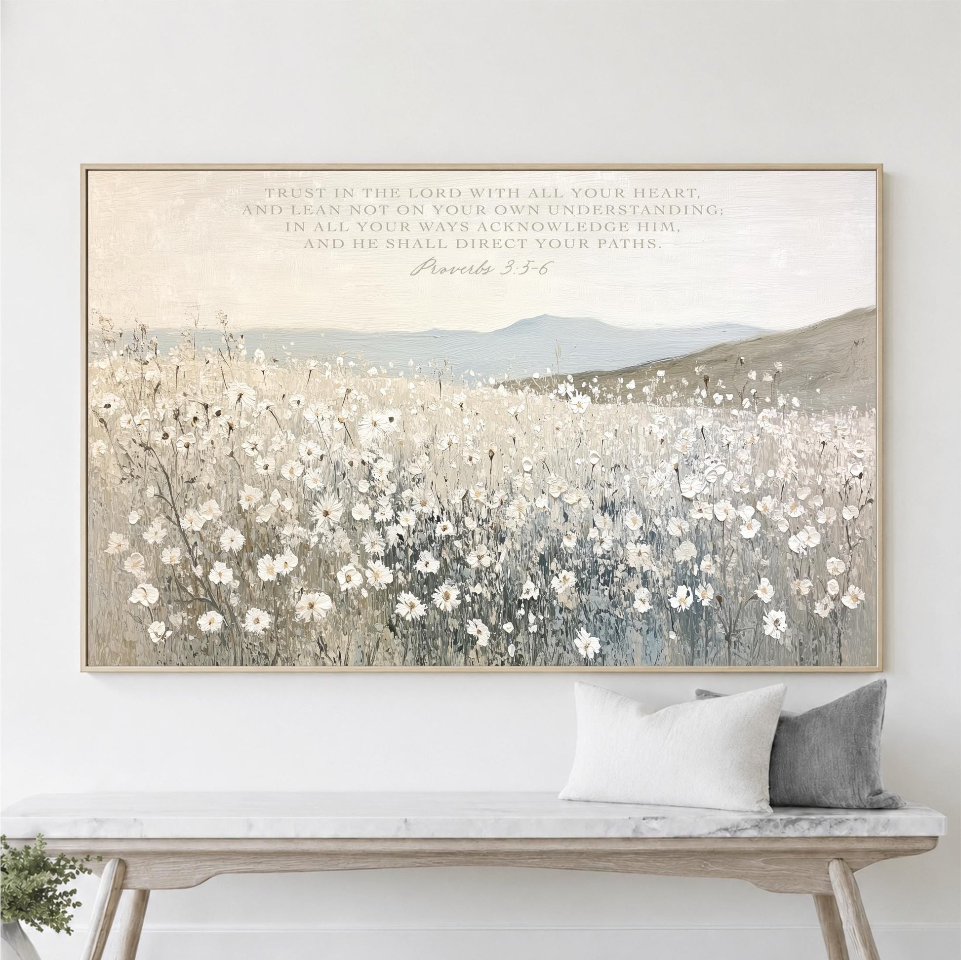 a large framed painting of a field of white flowers hanging on a wall above a wooden bench.