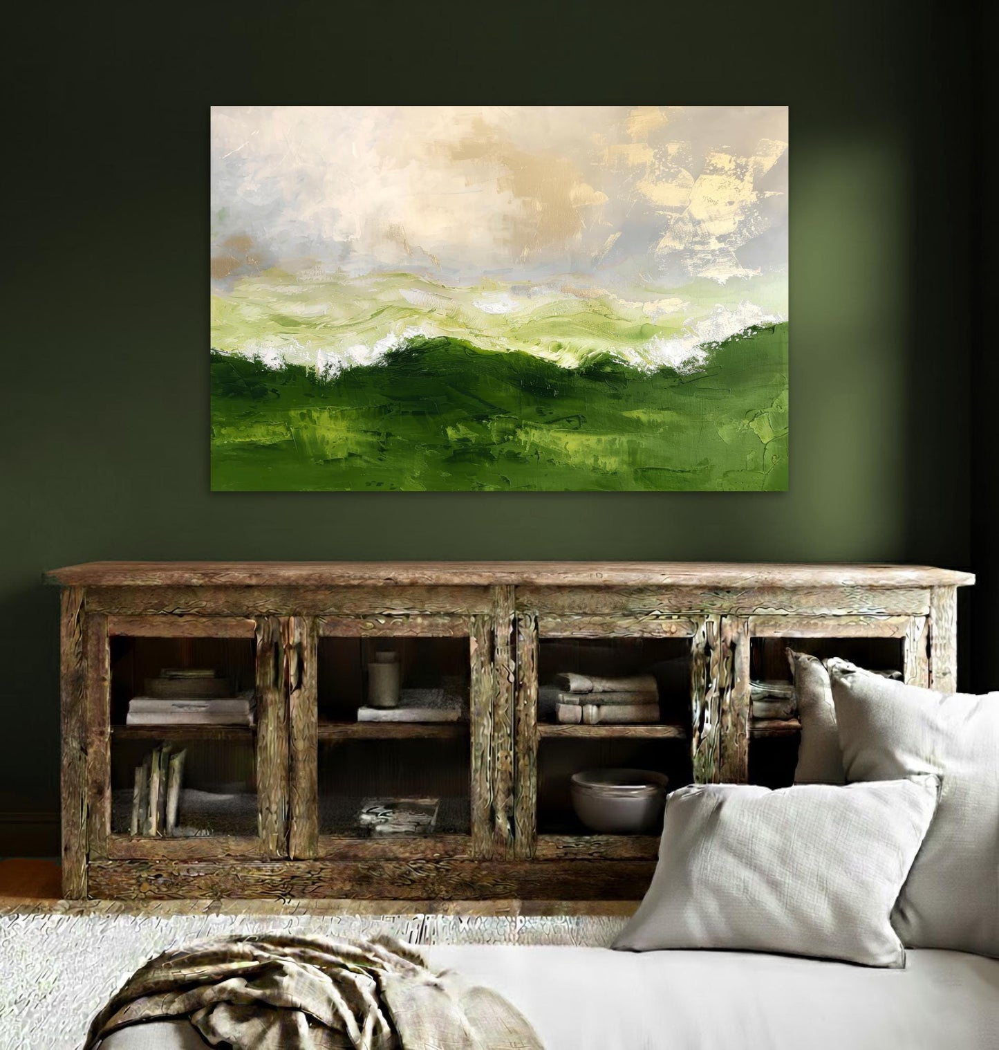 a large, vibrant painting of a green landscape hanging on a wall above a wooden cabinet with glass doors. The cabinet has several books and decorative items displayed on its shelves. The room has a cozy, inviting atmosphere with a couch and a rug in the foreground.