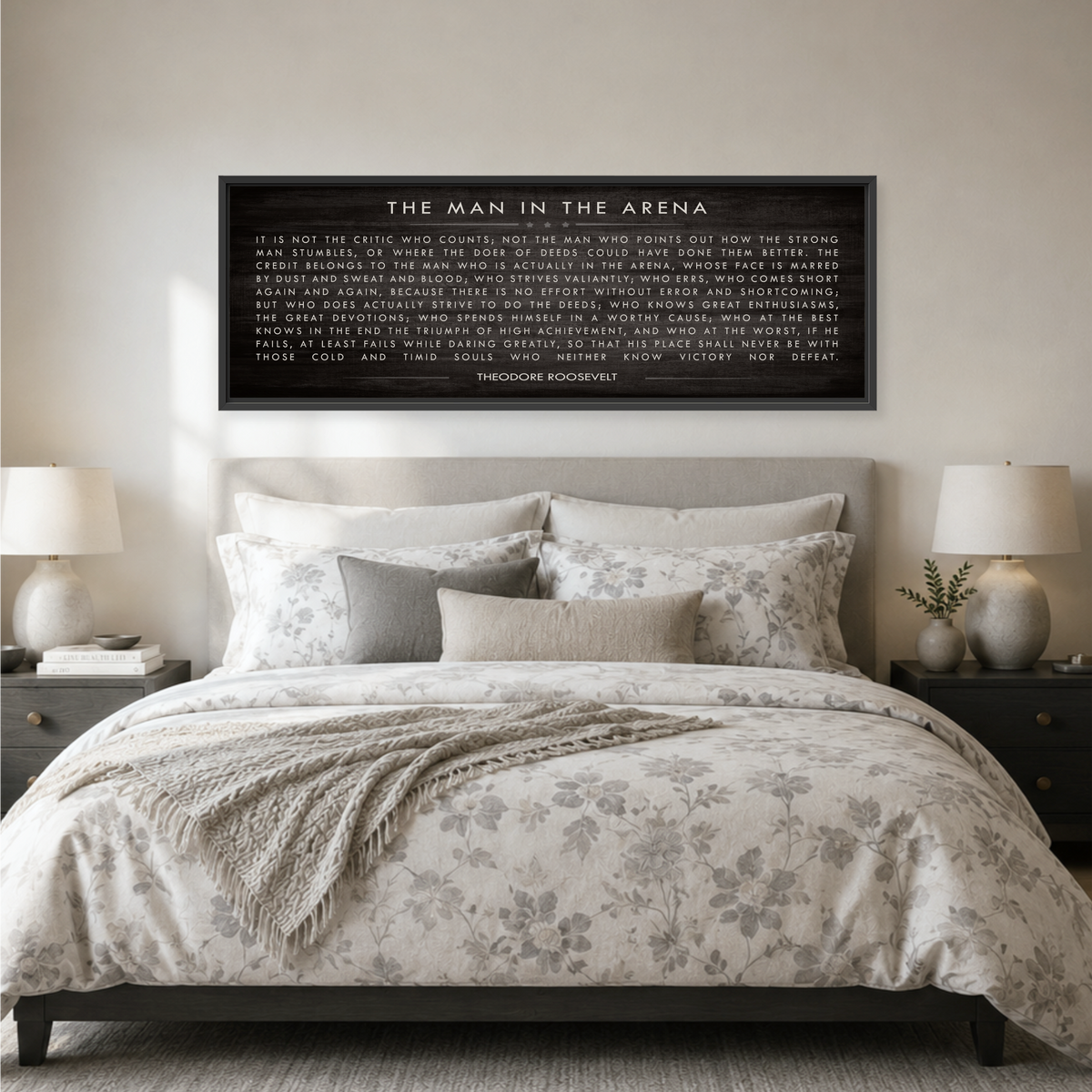 a bedroom with a large bed, a framed quote on the wall, and two lamps on nightstands.
