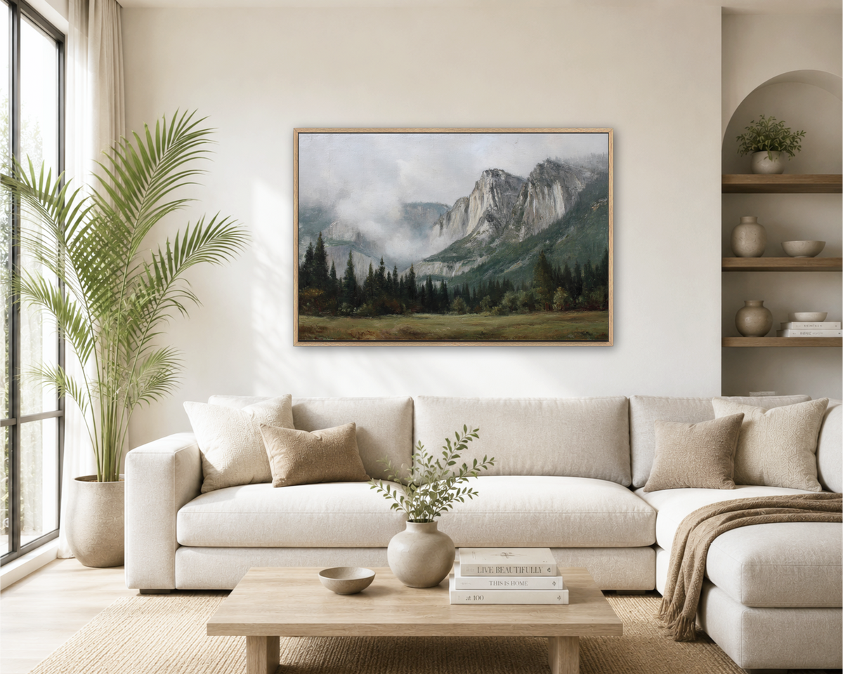 a serene living room with a large painting of a mountainous landscape hanging on the wall above a white sofa. The room is decorated with a potted plant, a vase with greenery, and a stack of books on a coffee table.