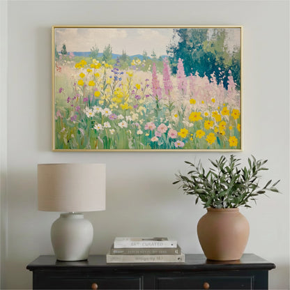 a painting of a colorful garden with flowers hanging on a wall above a wooden table with a lamp and a vase of greenery.