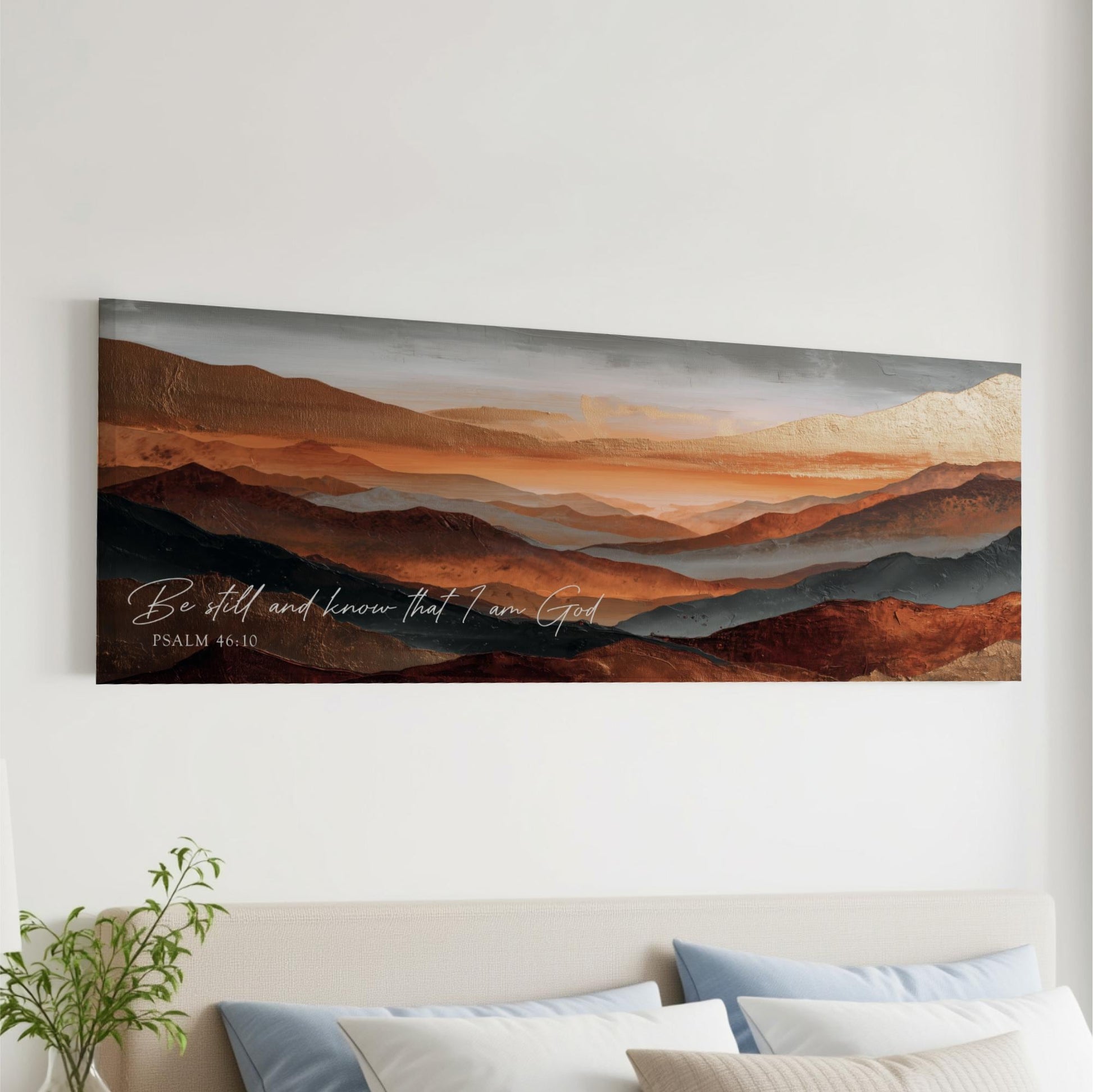 The image is a large painting or artwork depicting a mountainous landscape with a warm, orange and brown color palette. The painting is hung on a wall above a bed with pillows.