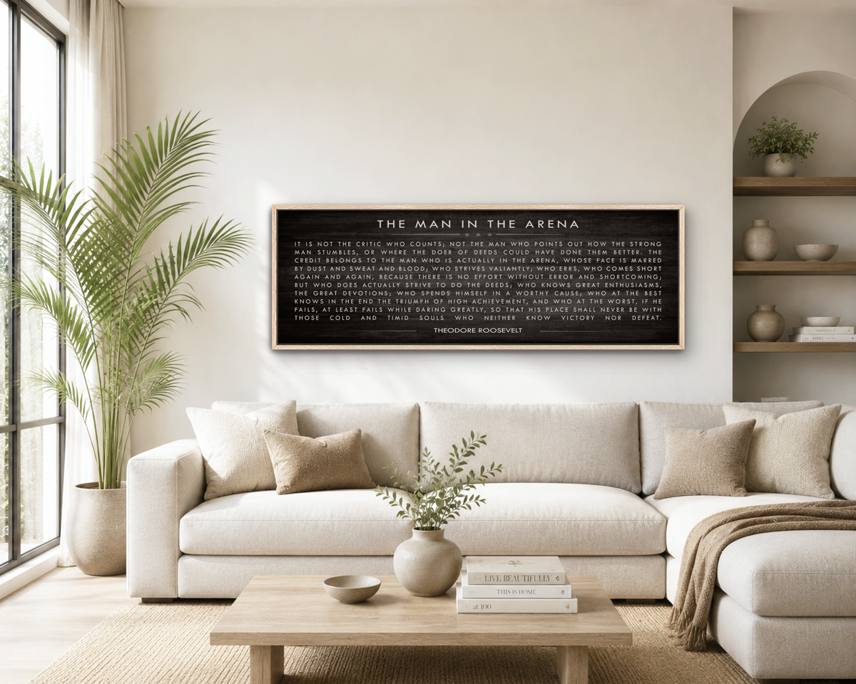 a living room with a large black framed text on the wall, a white sofa, a wooden coffee table, and a potted plant.