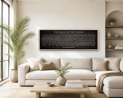 a living room with a large black framed text on the wall, a white sofa, a wooden coffee table, and a potted plant.