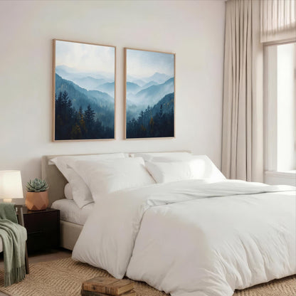 a serene bedroom with a large bed, white bedding, and two framed landscape paintings hanging above it. The paintings feature a mountainous, forested scene with a blue sky and misty atmosphere.