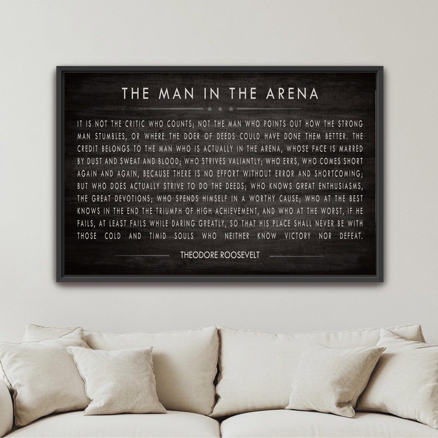 a framed quote by Theodore Roosevelt, a famous American president, mounted on a wall above a couch.