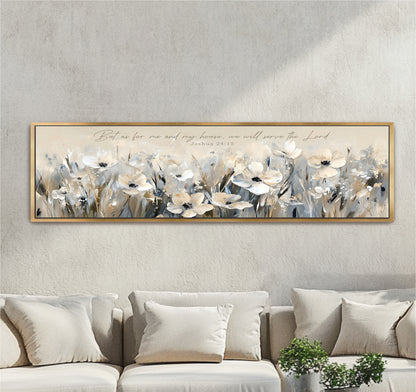 A framed painting of white flowers is hanging on a wall above a beige couch, with a potted plant in the foreground.