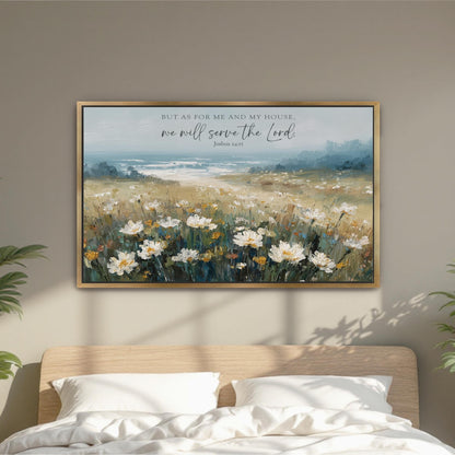 a framed painting of a field of flowers hanging on a wall above a bed with white pillows.