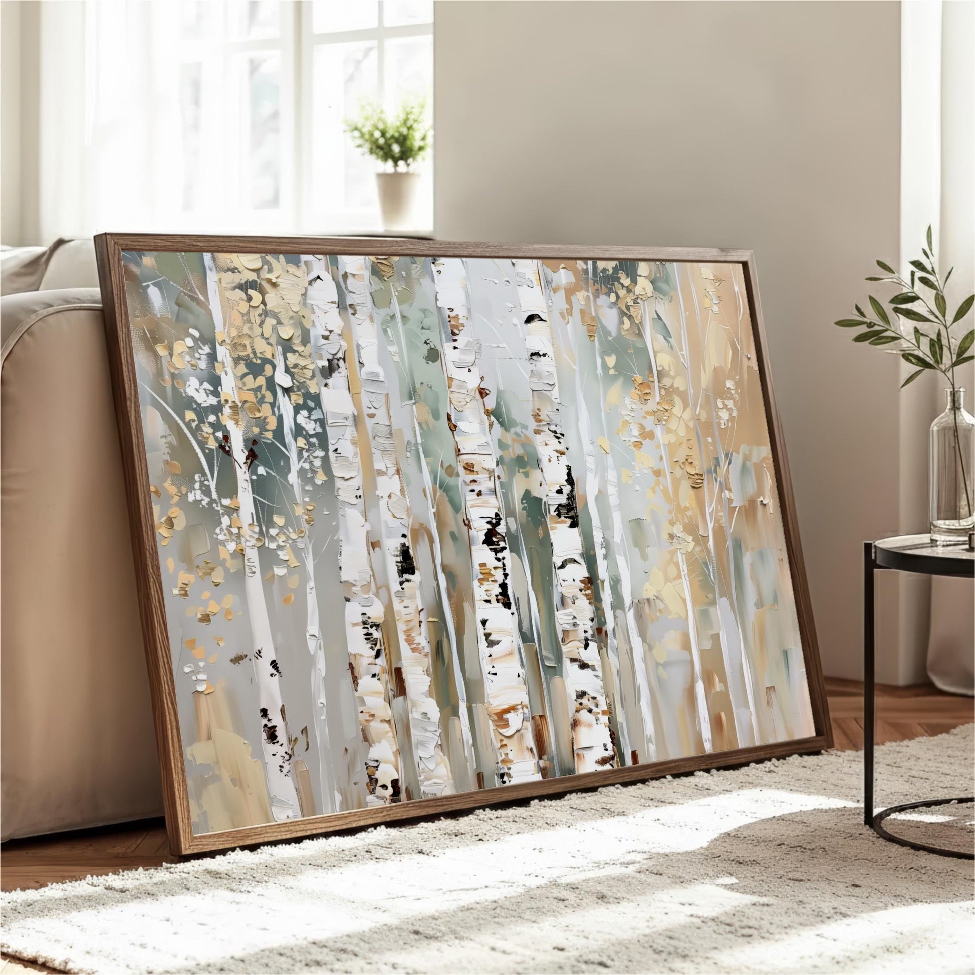 a large framed painting of a forest scene with birch trees, displayed on a wooden floor in a living room setting.
