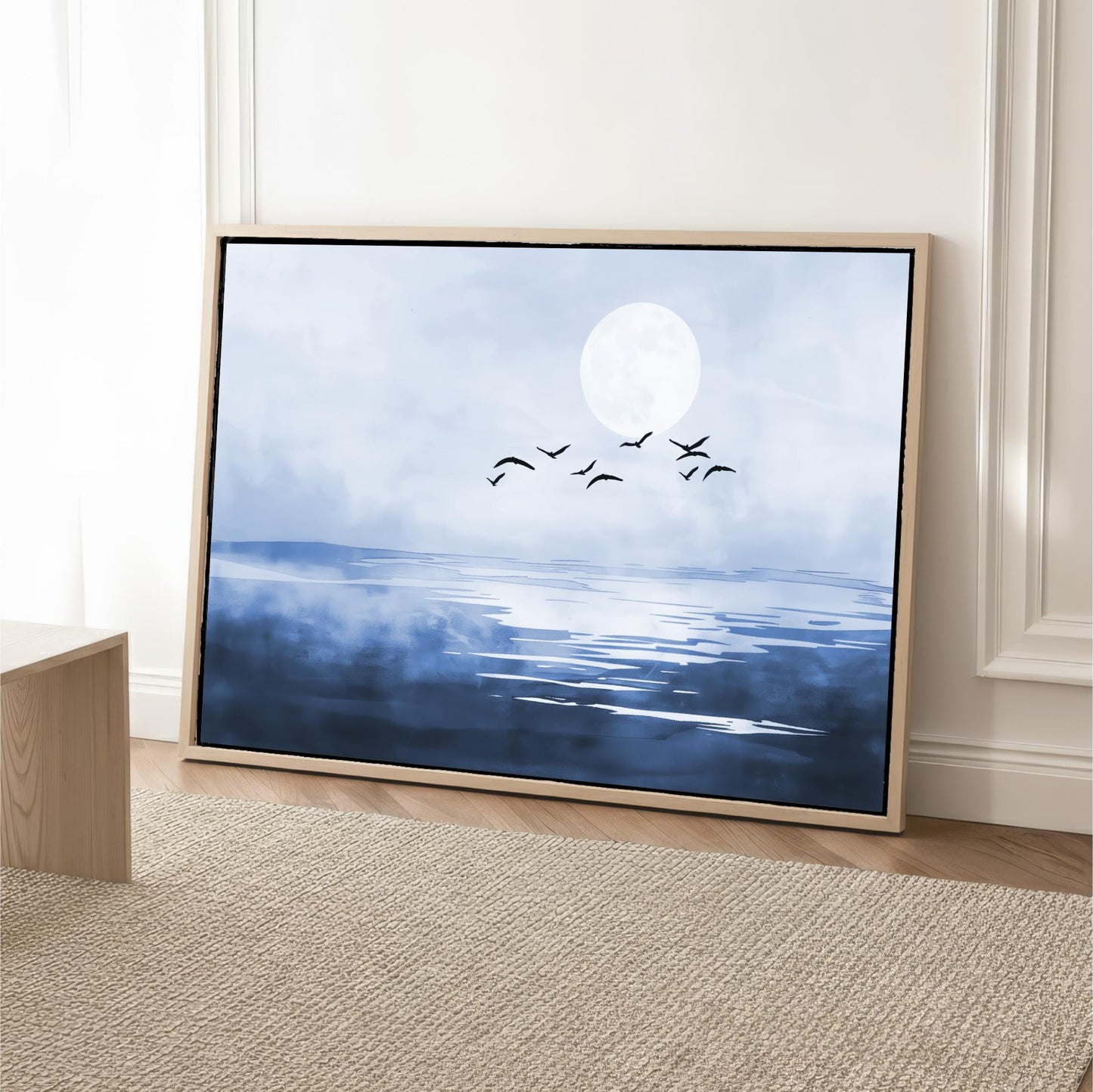 A framed painting depicting a serene landscape with a large moon, birds flying over a body of water.
