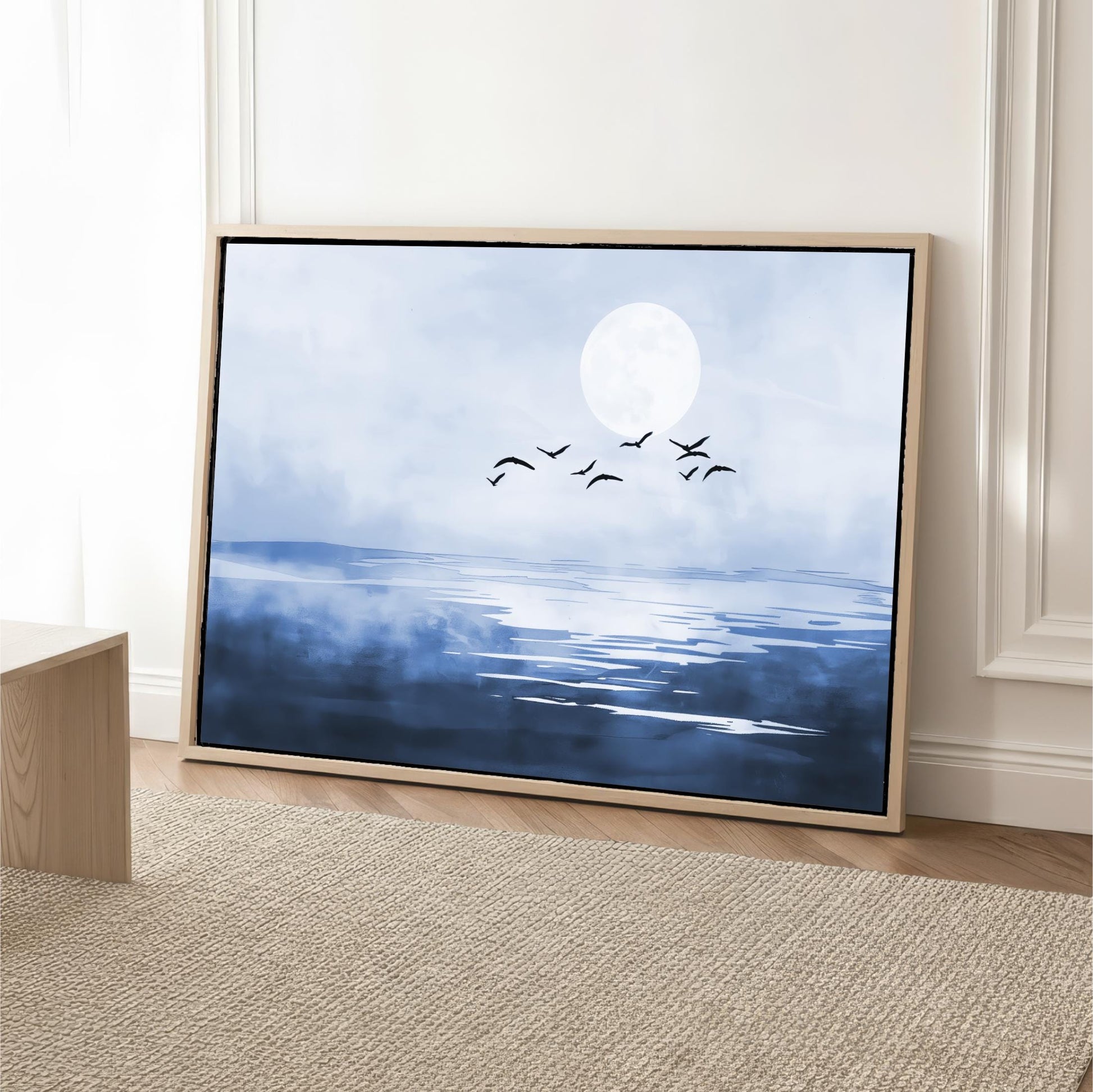 A framed painting depicting a serene landscape with a large moon, birds flying over a body of water.