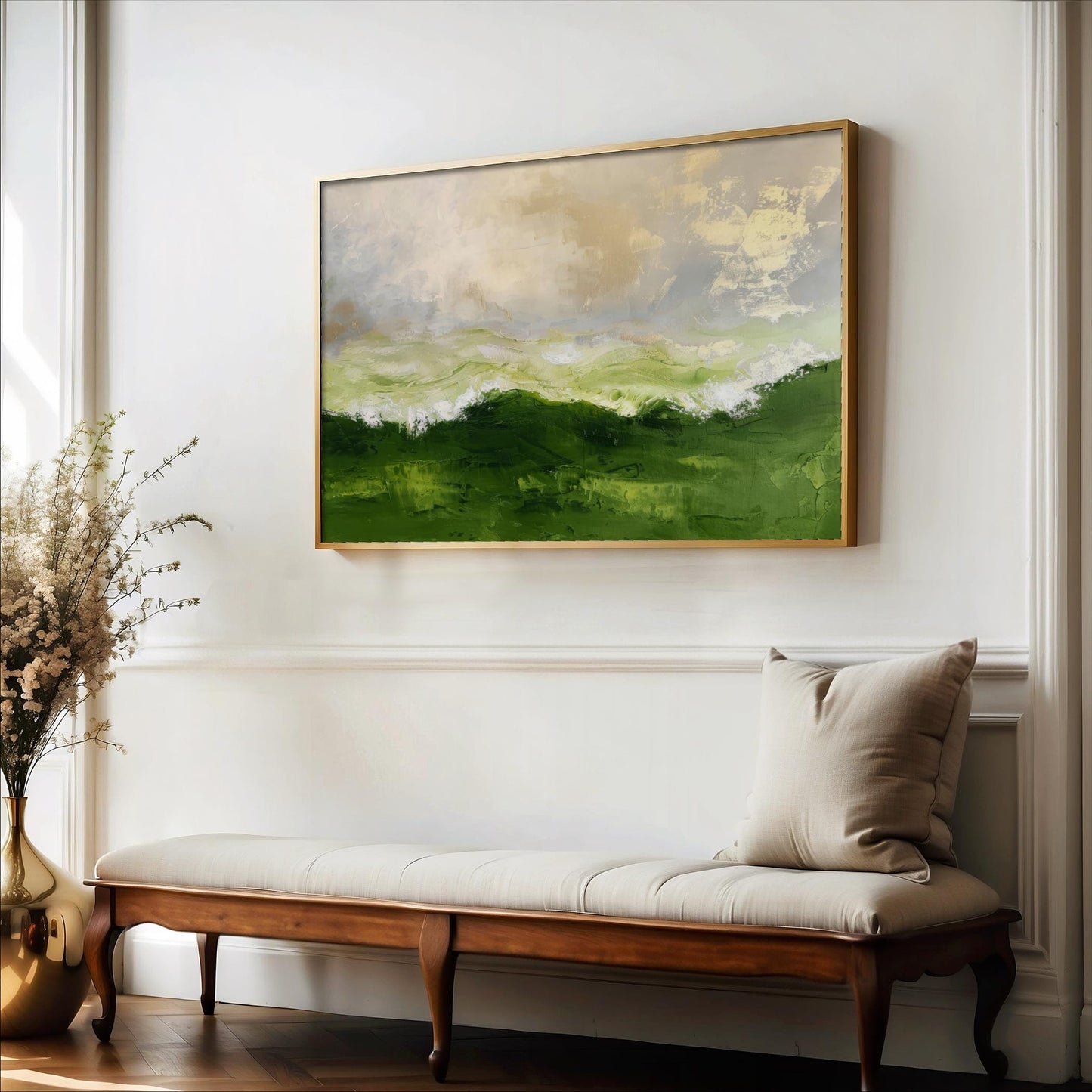 a large painting of a green landscape hanging on a white wall above a wooden bench with a beige cushion.