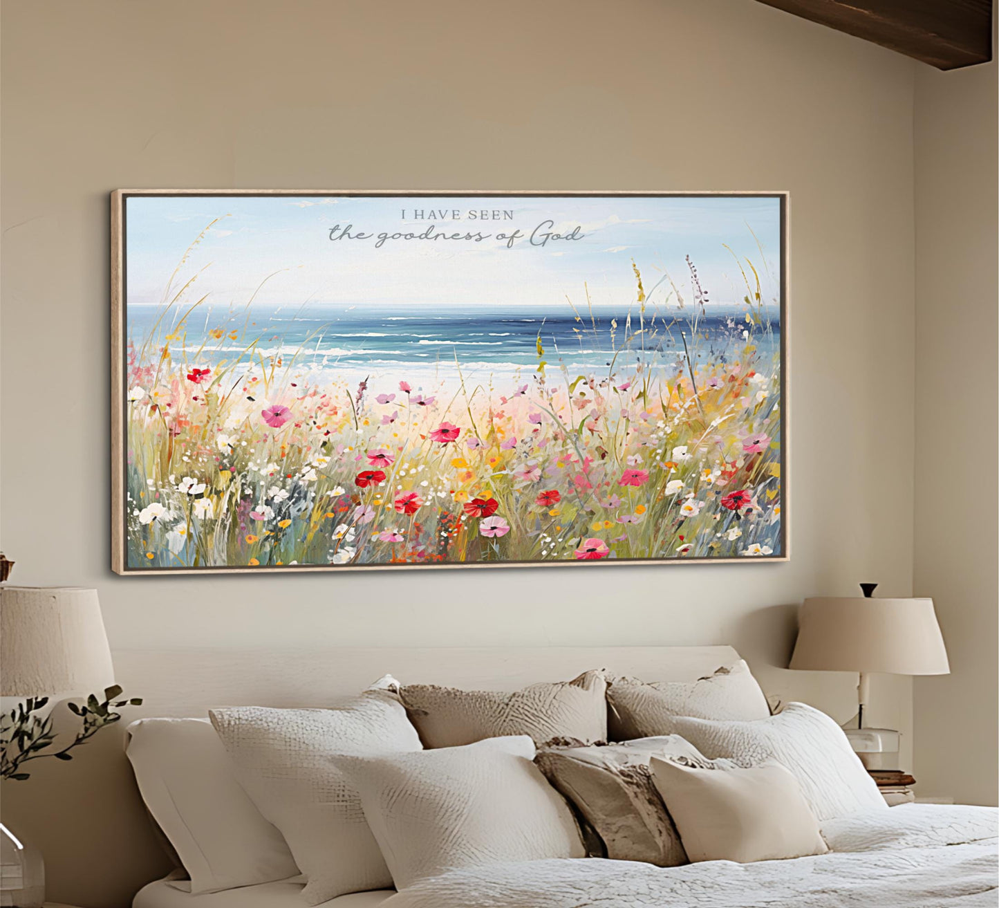 a large, framed painting of a field of colorful flowers hanging on a wall above a bed with white pillows and a beige headboard.
