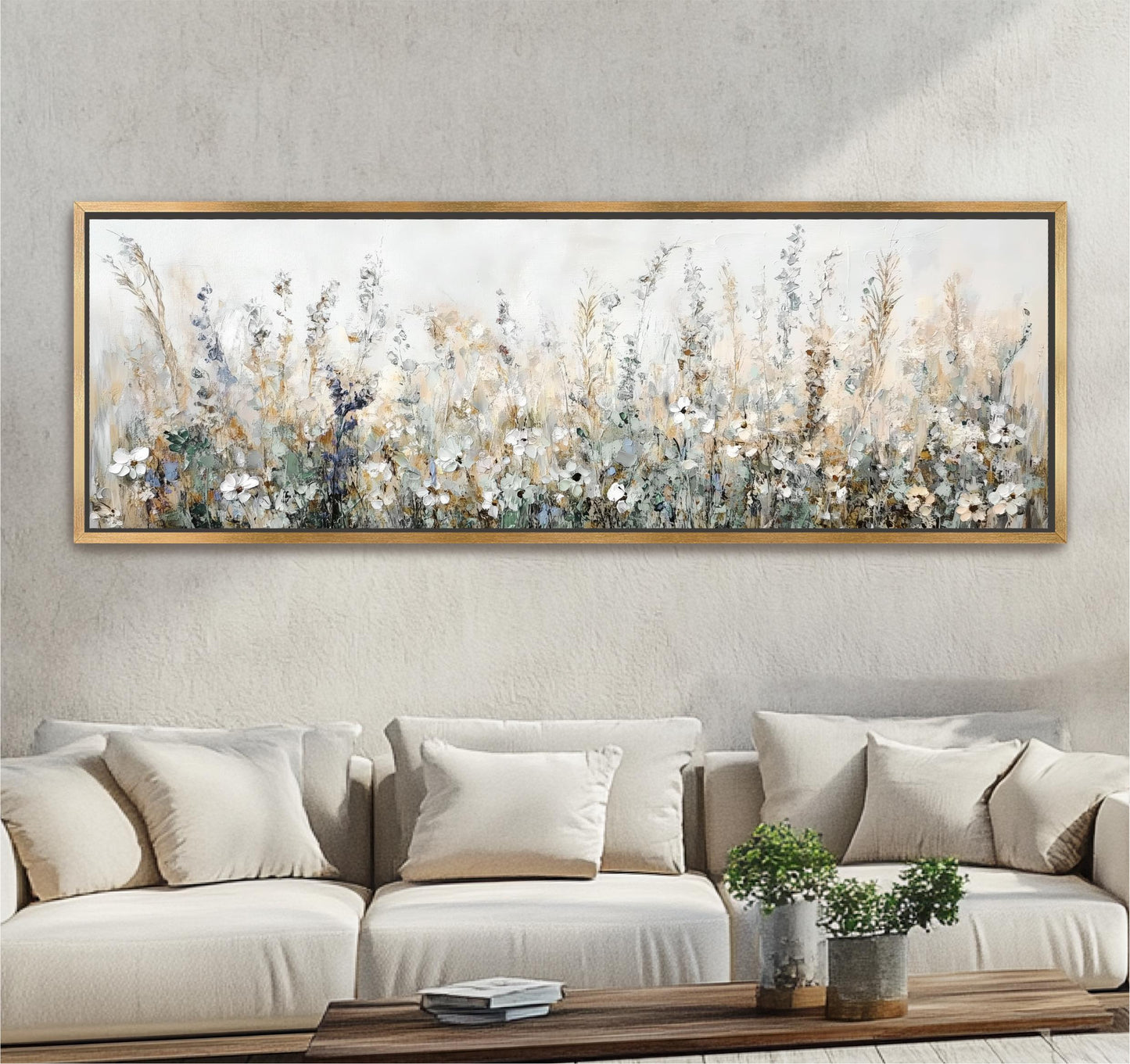 a large, framed painting of a field of flowers hanging on a wall above a beige sofa with white pillows.
