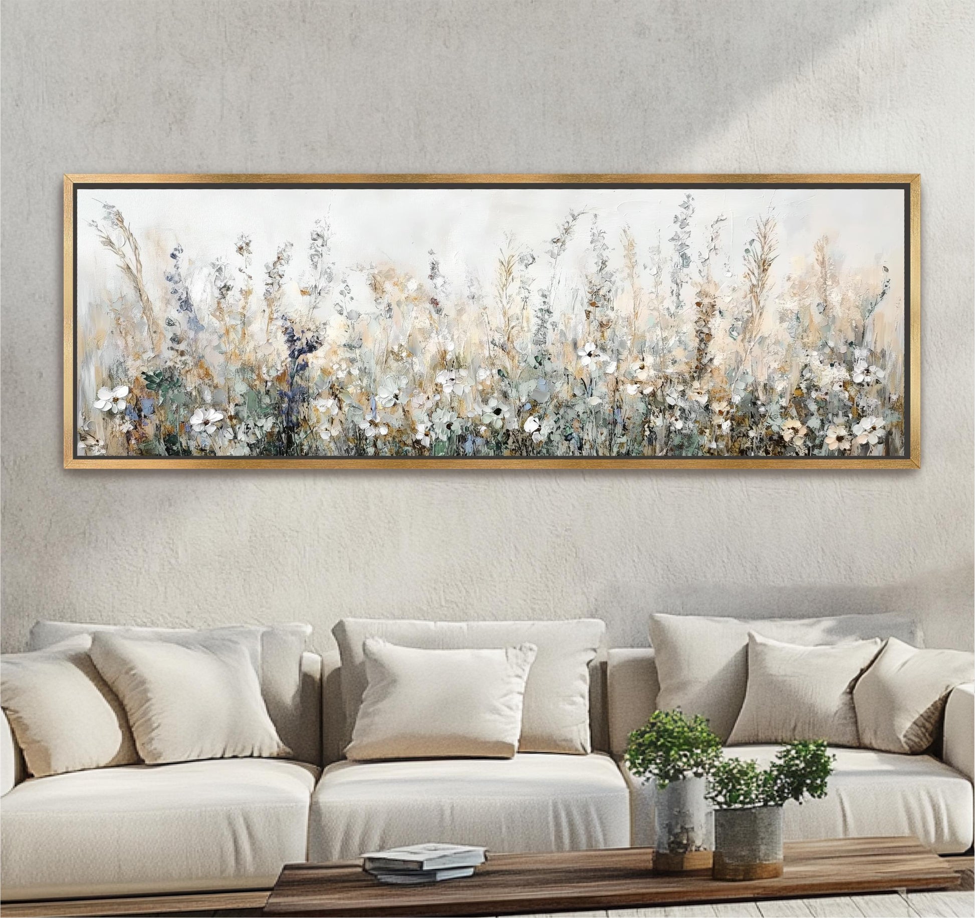 a large, framed painting of a field of flowers hanging on a wall above a beige sofa with white pillows.
