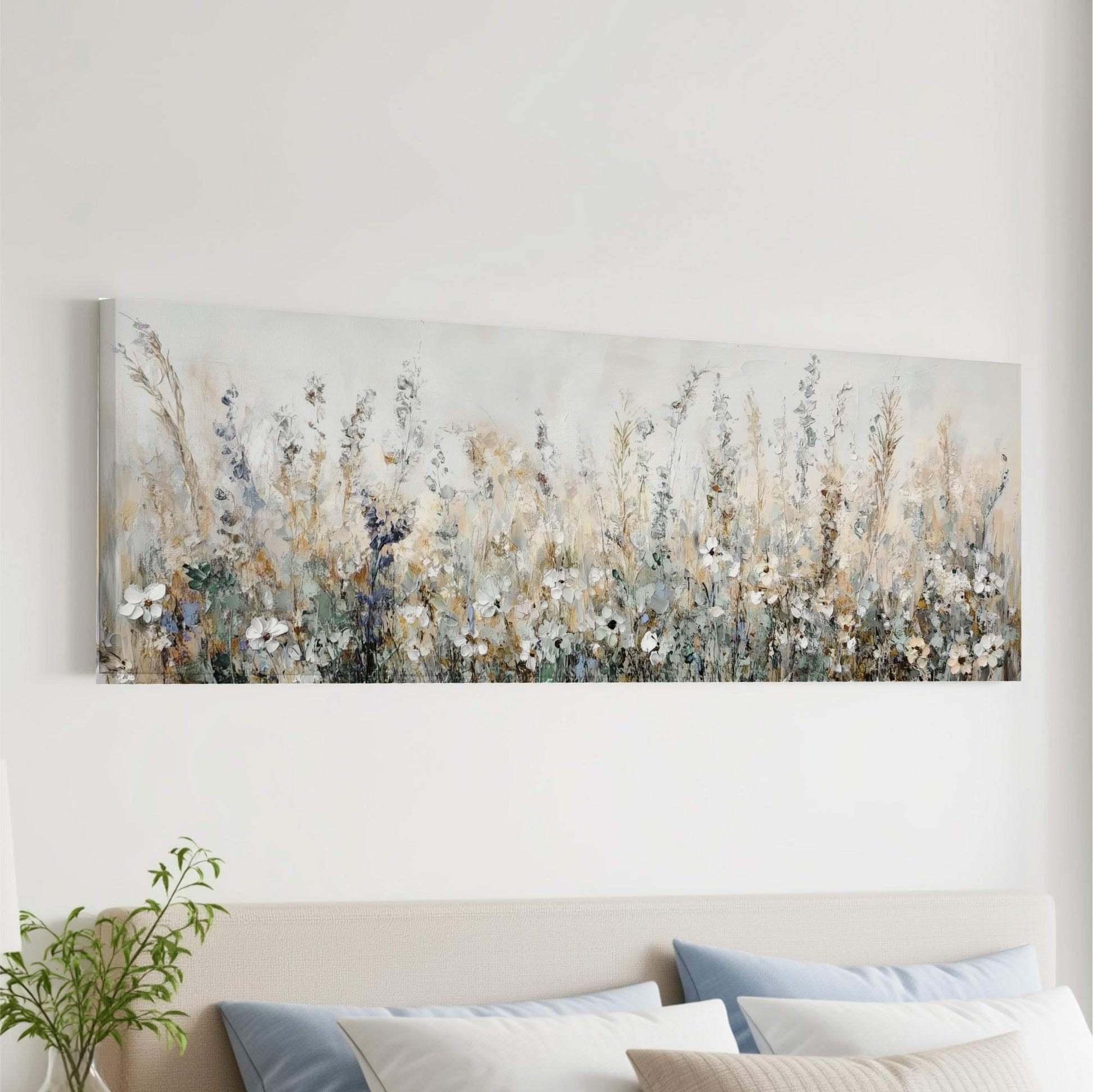 a large, long painting of a field of flowers hanging on a wall above a bed with pillows.