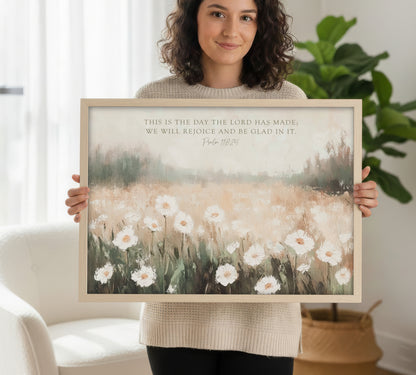 A woman is holding a framed print of a painting of a field of white flowers.