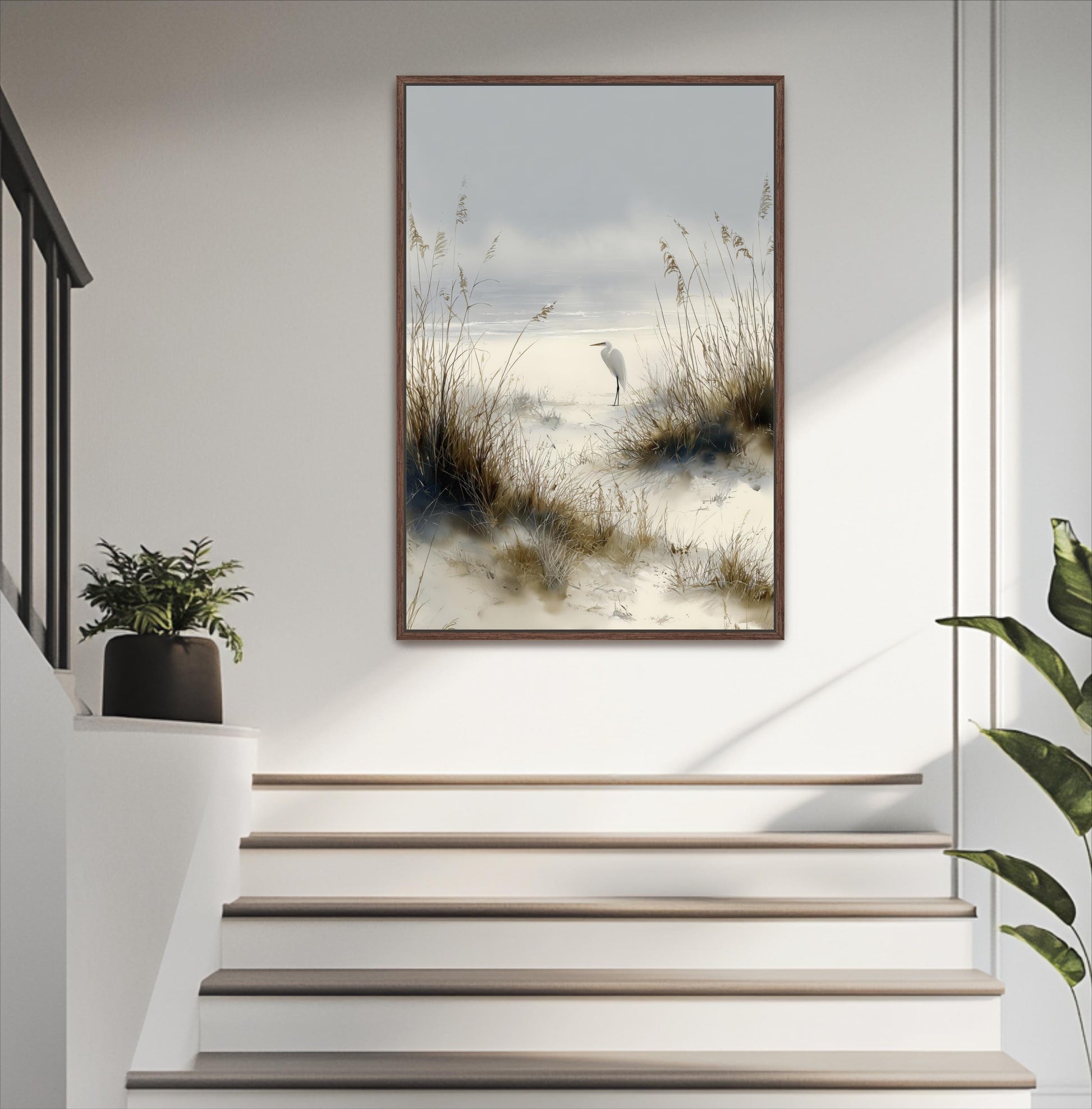 a serene scene of a bird standing on a beach, with a tall grassy area and a body of water in the background. The bird is positioned on the right side of the frame, facing towards the left. The photograph is framed and hung on a wall, adding a touch of nature and tranquility to the room.