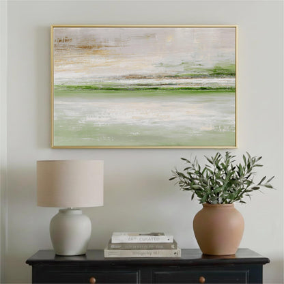 a framed landscape painting hanging on a wall above a black dresser with a lamp and a vase of greenery.