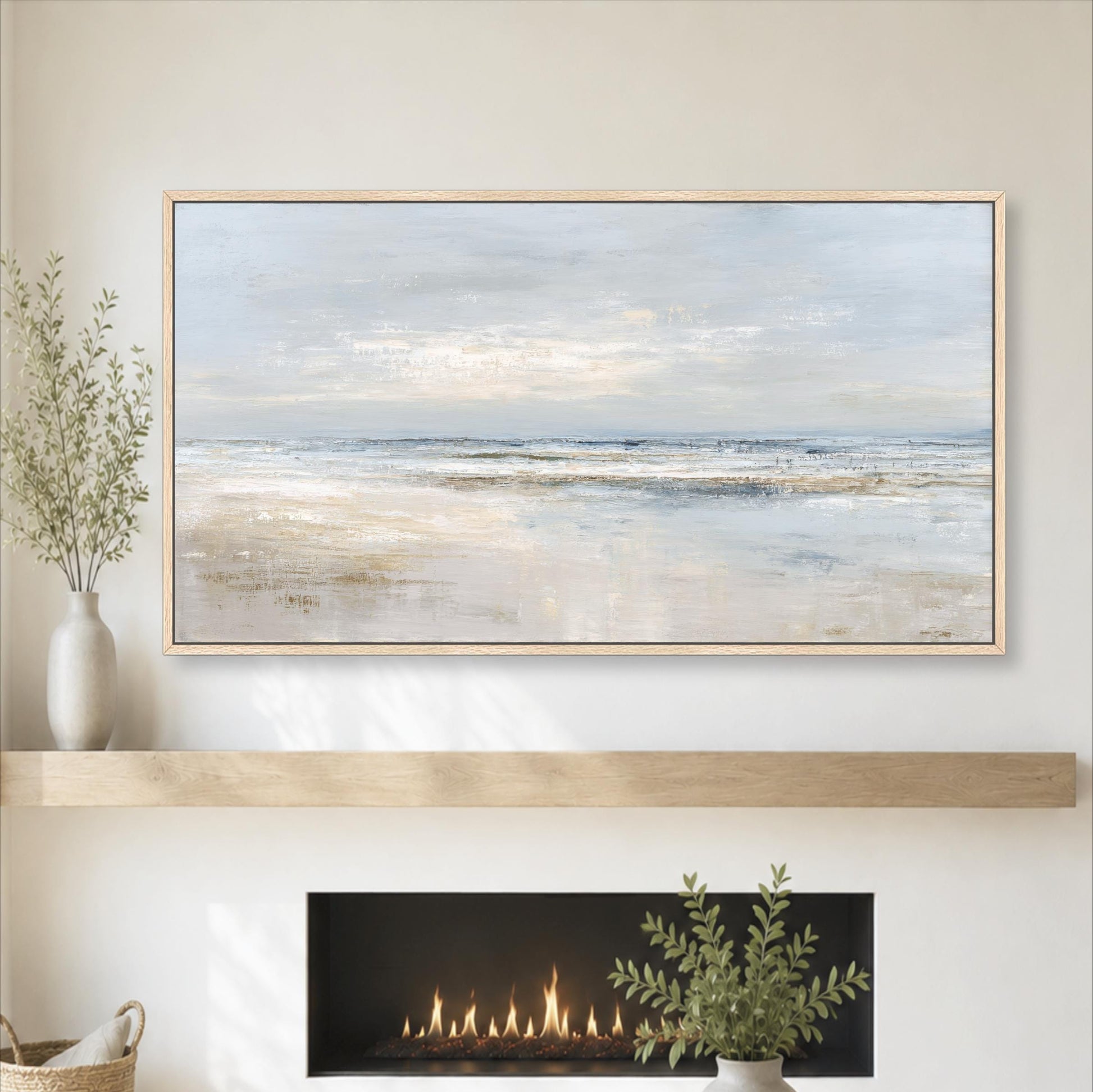 a large painting of a serene beach scene hanging on a wall above a fireplace. The painting depicts a tranquil beach with a calm ocean and a cloudy sky. The fireplace has a fire burning, adding warmth and ambiance to the room. The overall setting appears to be a cozy and inviting space, with the painting and fireplace as the focal points.