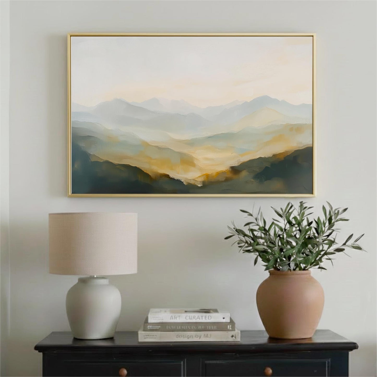 a framed landscape painting hanging on a wall above a black dresser with a lamp and a vase of greenery.