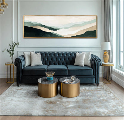 A modern living room with a blue tufted sofa, two round coffee tables, and a large landscape painting on the wall.
