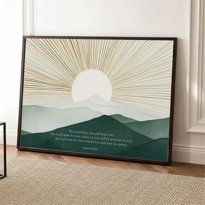 The image is a framed print featuring a serene landscape with mountains and a sunburst design. The text below the image reads "The Lord makes you and keep you, the Lord makes his face towards you and begrudgingly to you, the Lord turns his face towards you and gives you peace."
