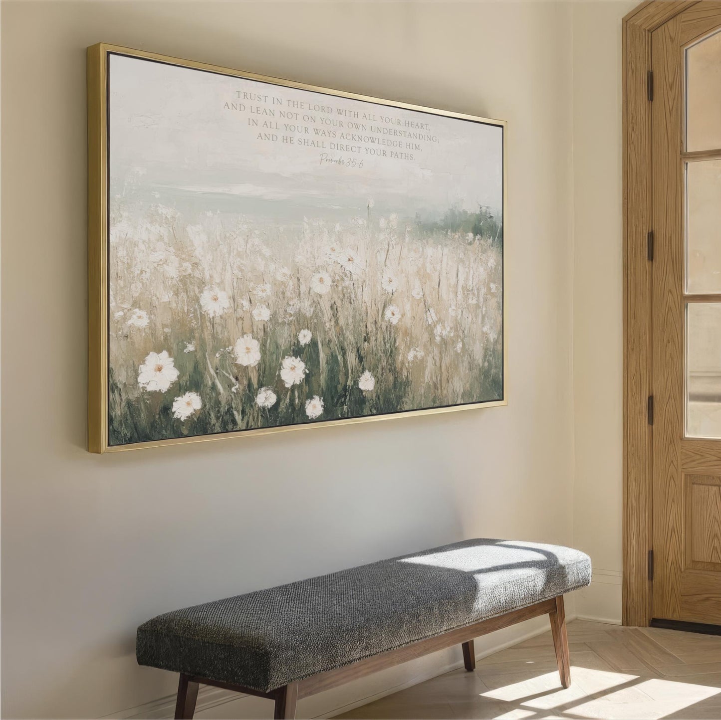 a large painting of a field with white flowers hanging on a wall, accompanied by a gray bench in the foreground.