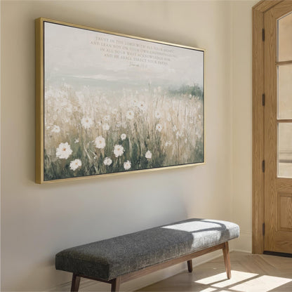 a large painting of a field with white flowers hanging on a wall, accompanied by a gray bench in the foreground.