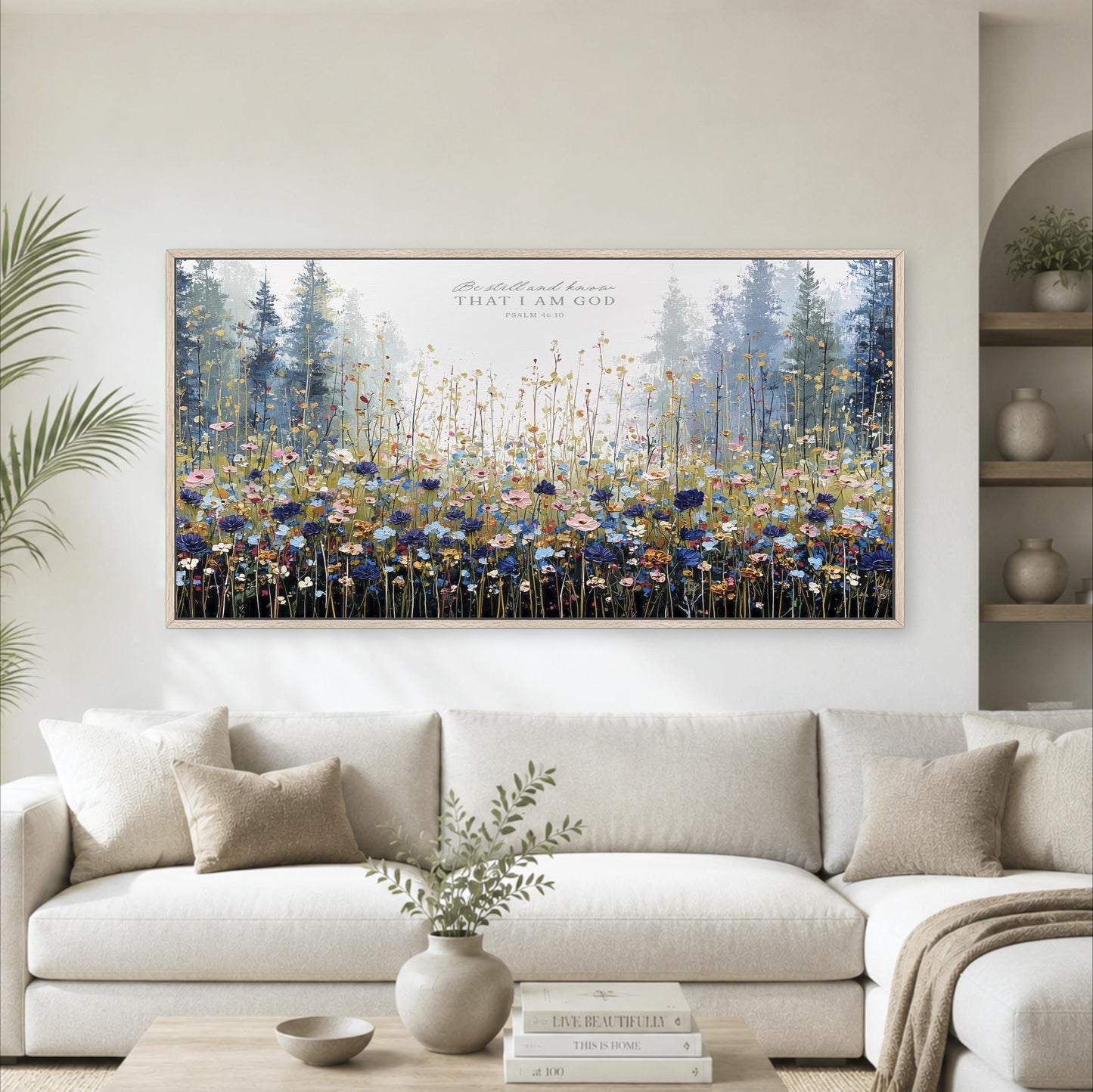 a large, framed painting of a field of flowers hanging on a wall above a white couch in a living room setting.