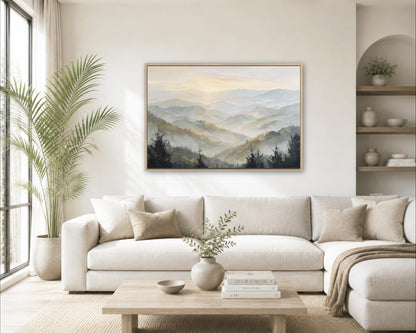 a serene living room with a large painting of a mountain landscape hanging on the wall above a white sofa. The sofa is adorned with throw pillows and a vase of greenery, creating a cozy and inviting atmosphere. The room also features a coffee table with books and a plant, adding to the overall aesthetic and comfort of the space.