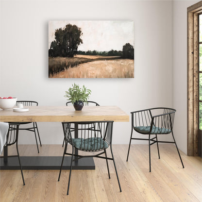 a dining room with a wooden table and black metal chairs. Above the table, there is a painting of a field with trees. The room has a minimalist and modern design, with a large window providing natural light.
